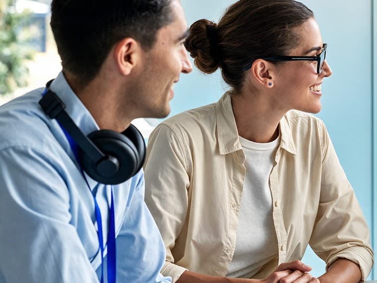 Two colleagues at a training table, turned towards someone off-frame and listening.